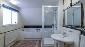 Un bagno moderno con vasca, doccia e lavandino, dotato di un ampio specchio e una finestra.