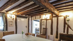 Una sala da pranzo con un tavolo rotondo, travi in legno e vista su un'altra stanza.