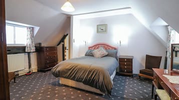 A bedroom with a bed, dresser, chair, and a small table.