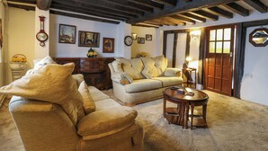 Un soggiorno accogliente con soffitto alto, travi a vista in legno, un camino e una porta in legno tradizionale.