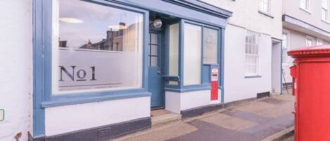 A building with a blue and white facade, a red post box, and a sign reading "No 1".