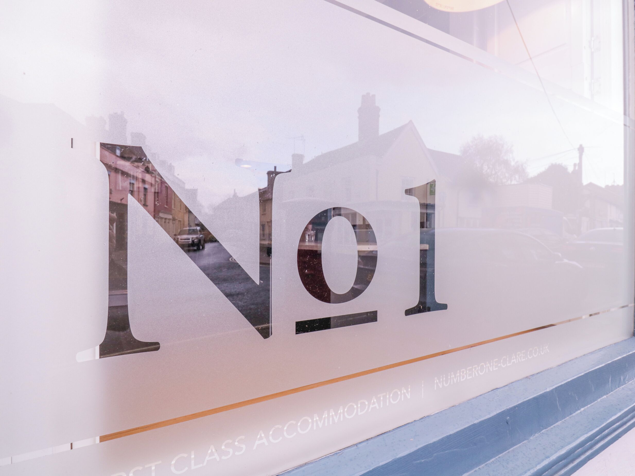Una ventana con un diseño de vidrio esmerilado que muestra el texto "No1" y "ALOJAMIENTO DE CLASE | NUMBERONECLARE.CO.UK".