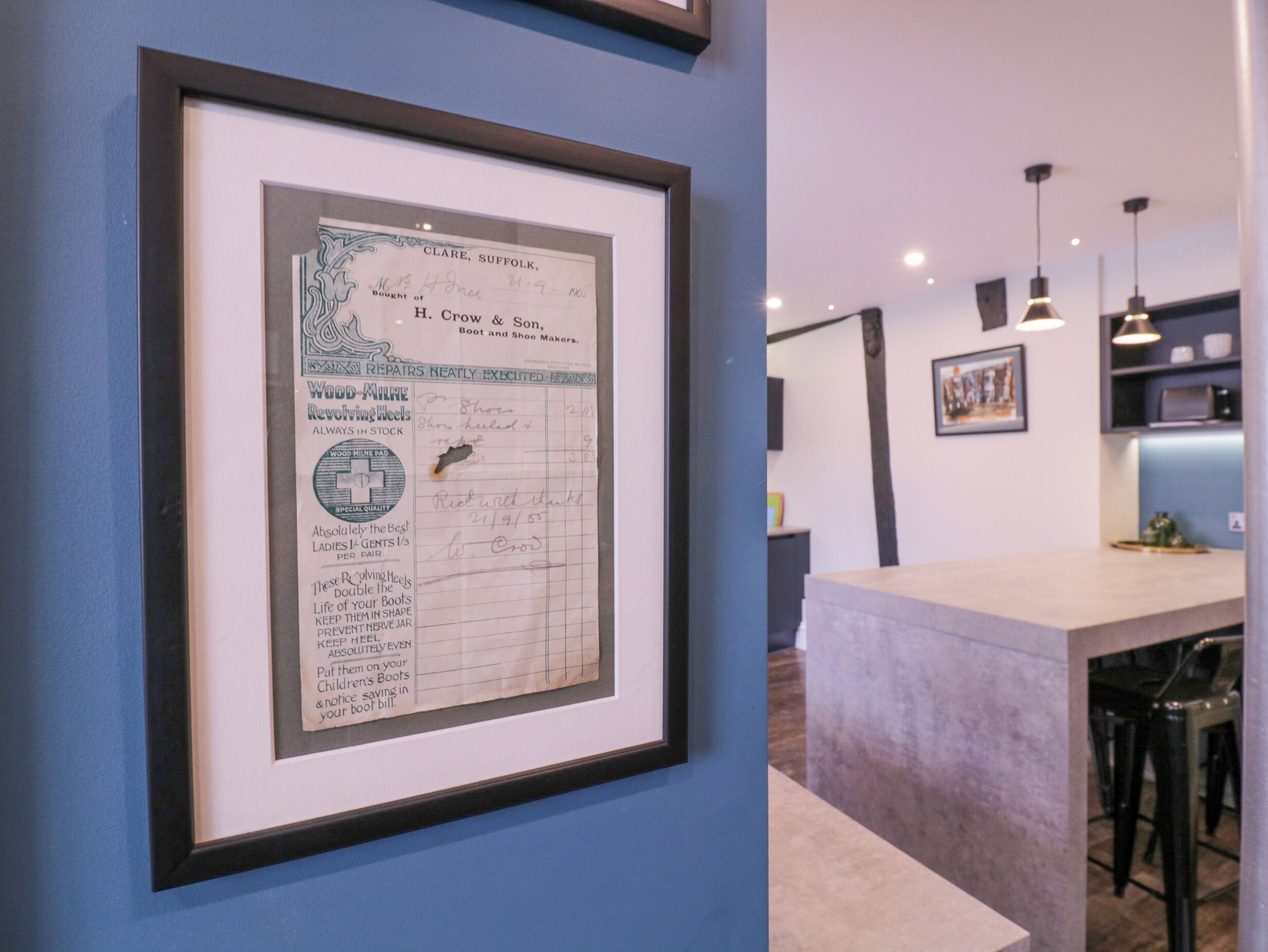 Un documento histórico enmarcado en una pared, una zona de bar con taburetes e iluminación colgante.