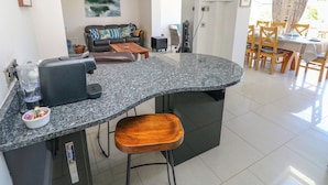 A modern kitchen with a granite countertop, a coffee machine, and a wooden stool. - Llain Gwynfor (Haverfordwest)