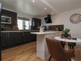 Una cocina moderna con armarios oscuros, una encimera blanca, un microondas integrado y un reloj grande en la pared.