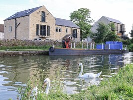 Un canal con un cisne nadando, una barca amarrada a la orilla y edificios de piedra con ventanas y balcones.