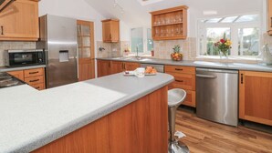A modern kitchen with wooden cabinets, stainless steel appliances, a large island, and a skylight.