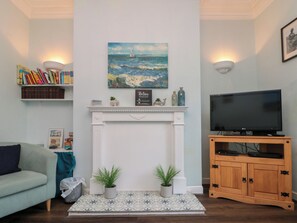 A living room with a fireplace, a television, and a bookshelf. - Holyrood Lodge (Bridlington)