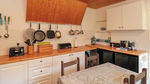 A kitchen with wooden cabinets, a wooden ceiling, and a dining area with a table and chairs.