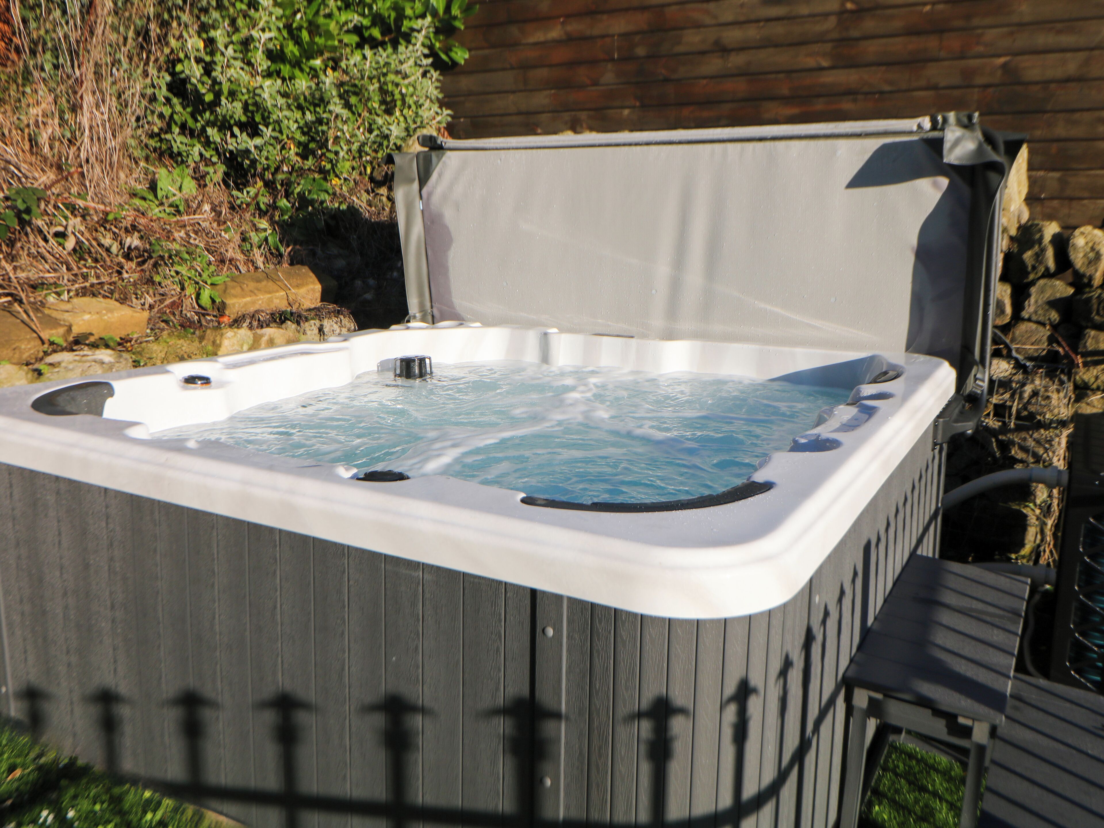 Un jacuzzi con revestimiento de madera, asiento incorporado y tapa.