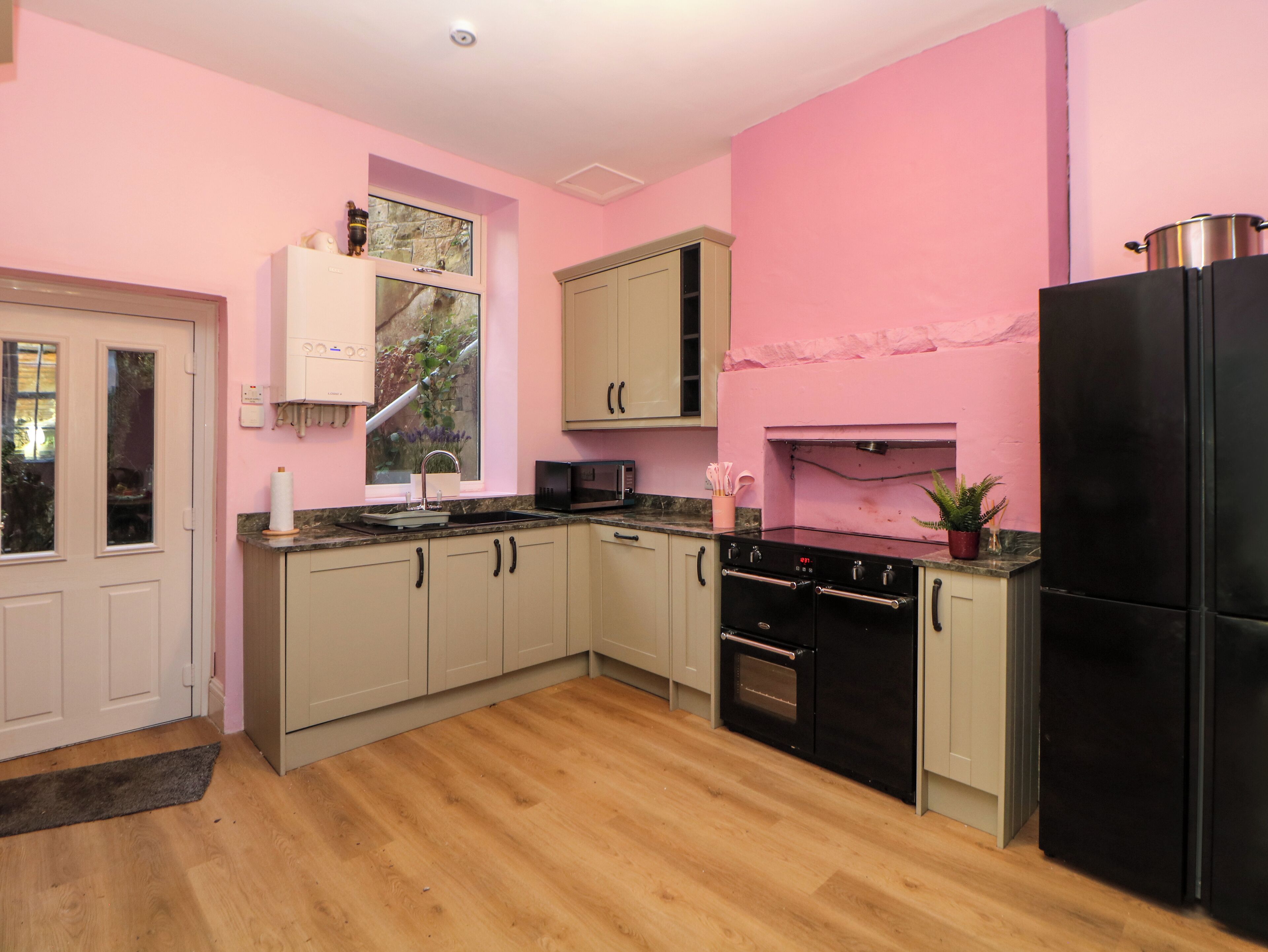 A kitchen with light wood flooring, a black refrigerator, a stove, and a microwave.