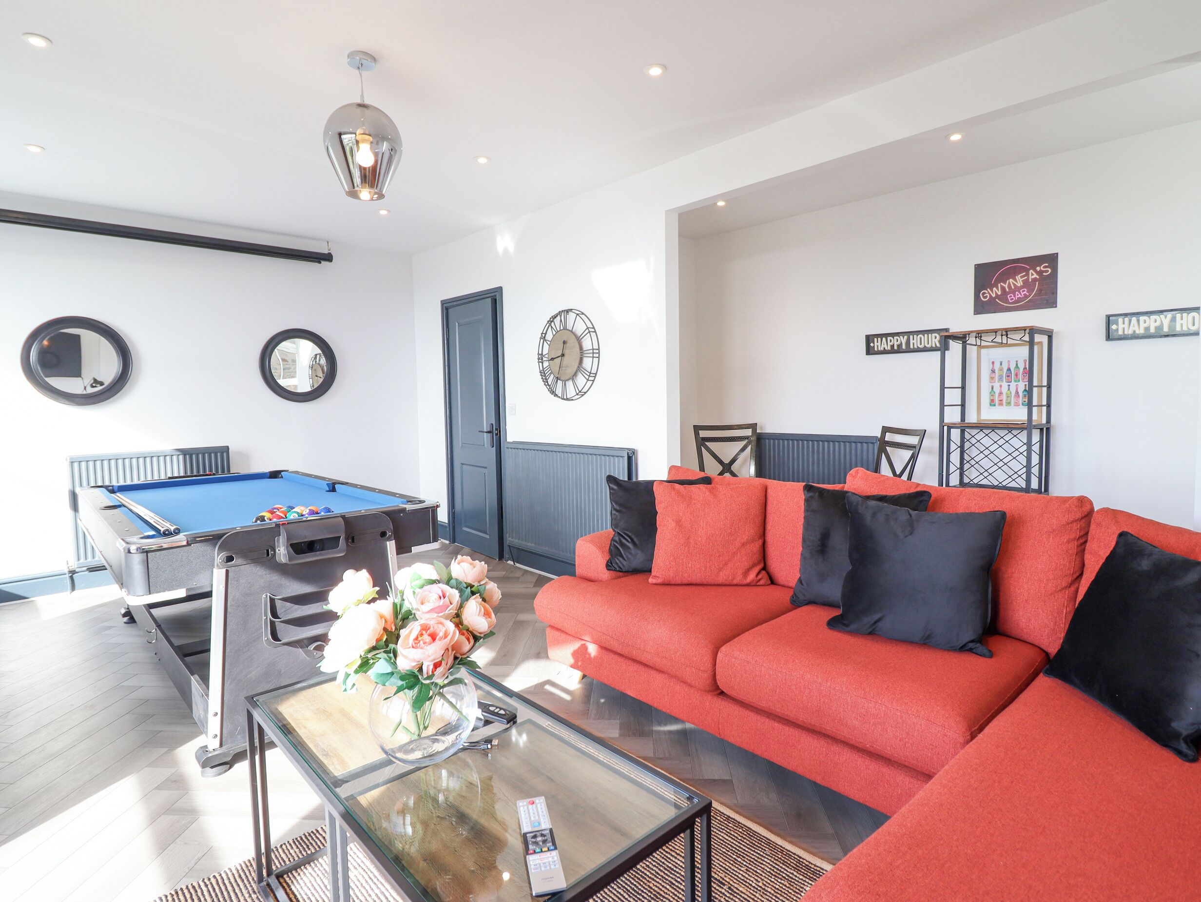 A modern living room with a pool table, red sofa, and a glass coffee table.