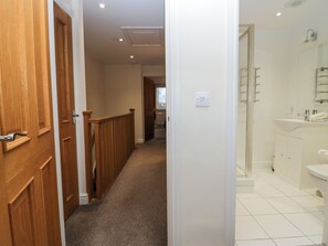 A hallway leading to a bathroom with a shower and sink. - 4 Teal House (Carnforth)