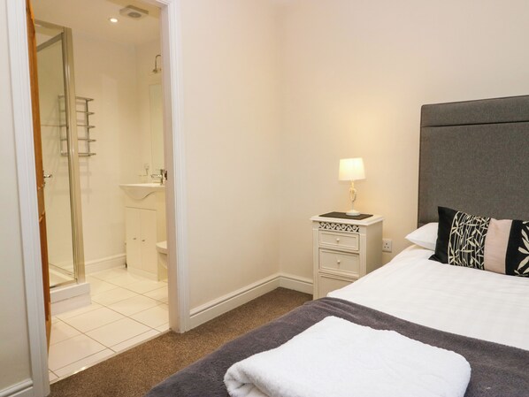 A hotel room with a bed, a bedside table with a lamp, a bathroom with a shower, and a toilet.