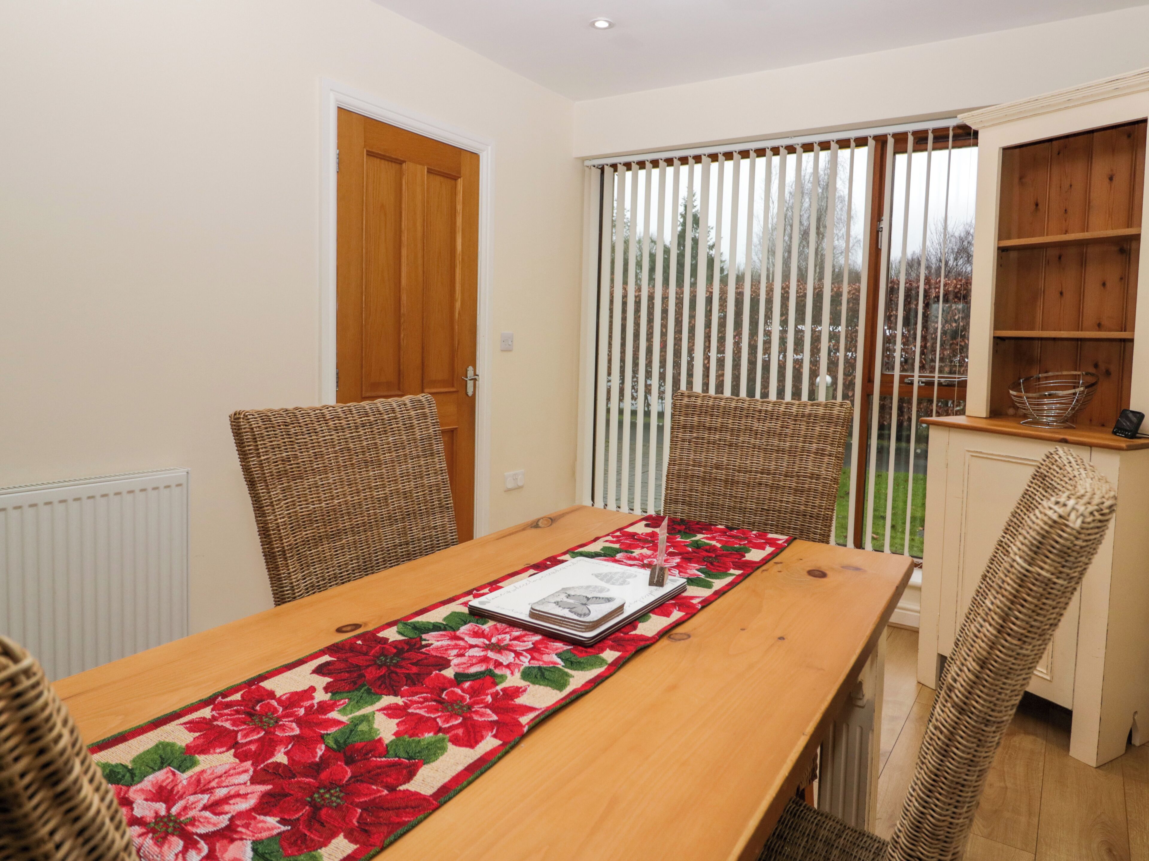 A dining area with a wooden table, wicker chairs, and a floral table runner.