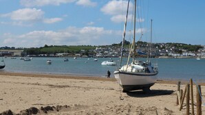 A sandy beach with a sailboat anchored near the shore. - Berry Bay (Bideford)