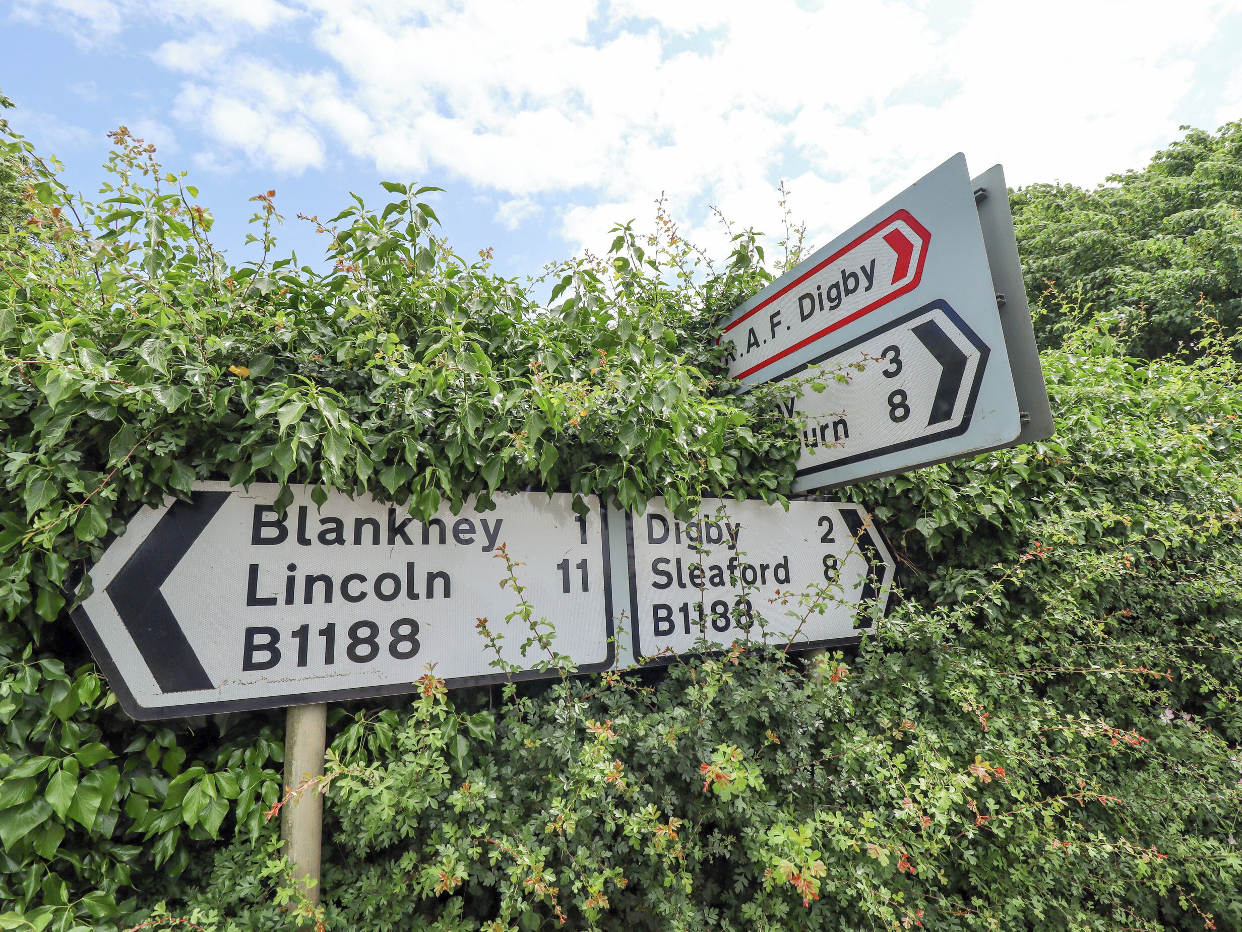 A directional road sign with multiple destinations and distances.