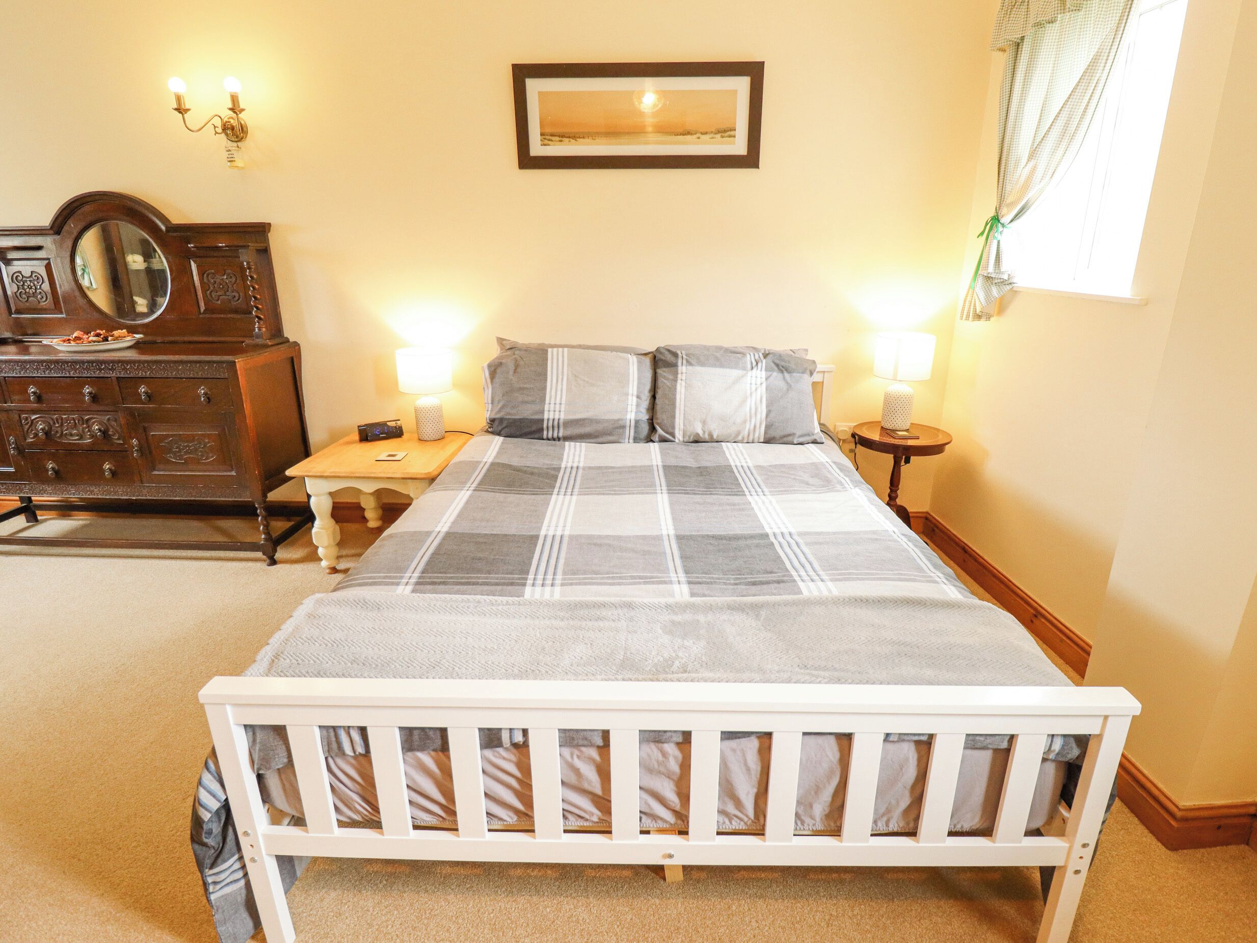Une chambre à coucher avec un lit, une commode, des tables de chevet et un tableau encadré au mur.