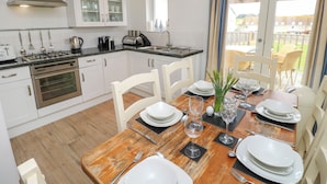 A modern kitchen with white cabinets, a built-in oven, and a gas stove. - Munday H2 (Yarmouth)