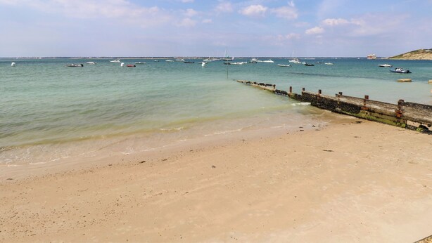 A beach with a sandy shore and a pier extending into the water. - Munday H2 (Yarmouth)
