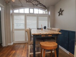 Uma sala de jantar com mesa de madeira, cadeiras e um banco.