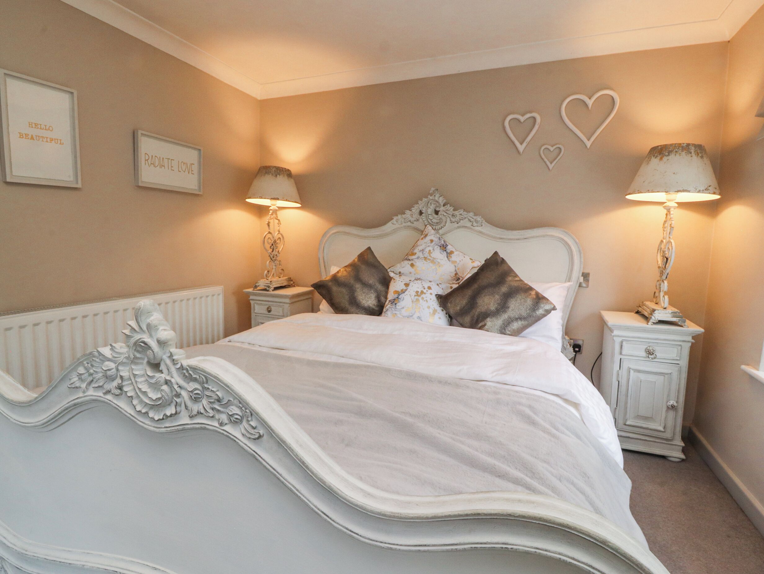 A bedroom with a large bed, two bedside tables with lamps, and decorative wall art.