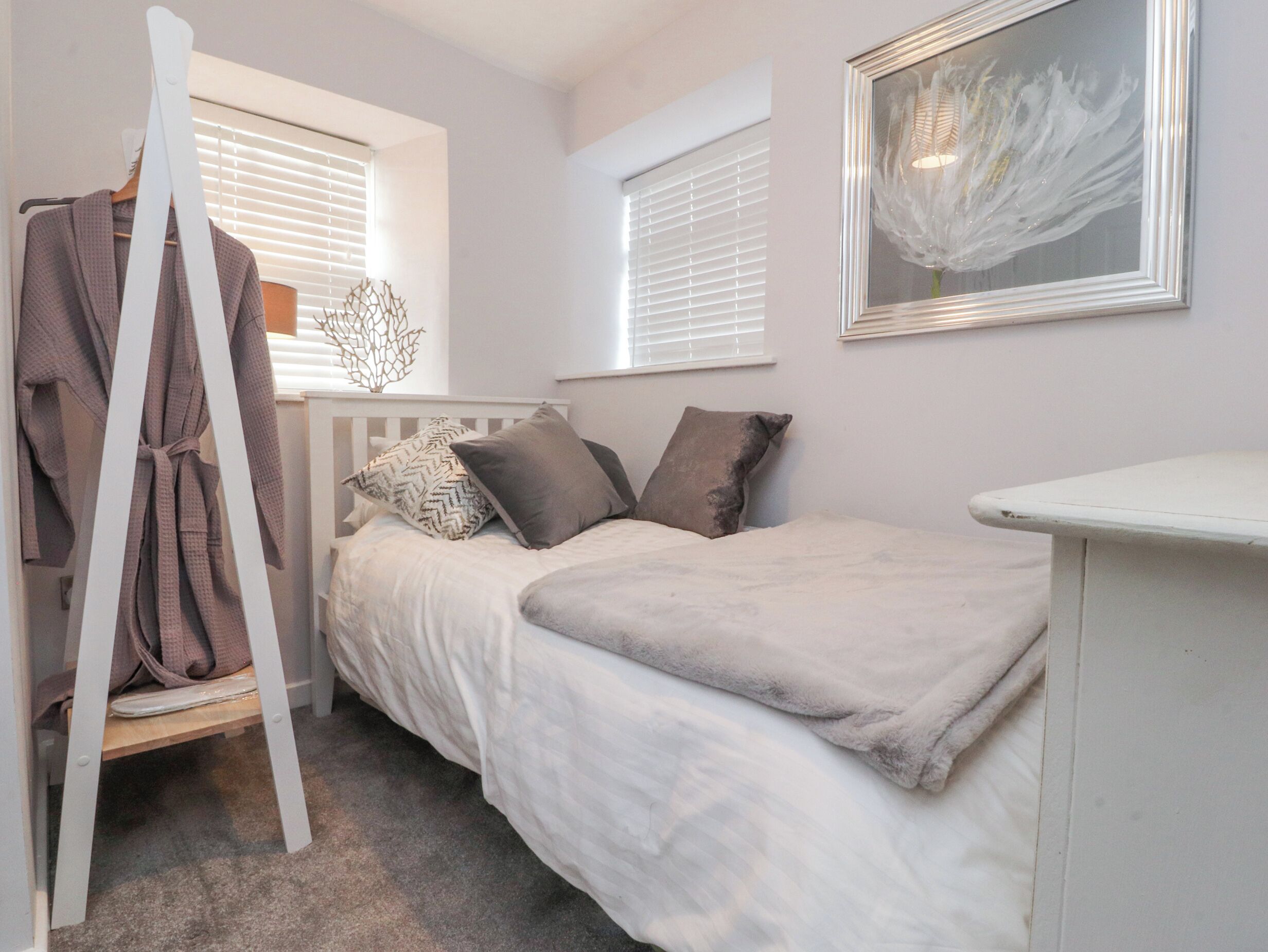 Une chambre à coucher avec un lit, un porte-manteau et un tableau au mur.