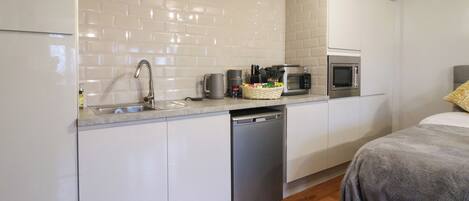A compact kitchen with white cabinets, a stainless steel sink, a microwave, and a dishwasher.