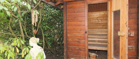 A wooden cabin with an open door revealing a wooden bench inside.