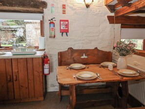 A wooden dining table set with plates, cutlery, and a fire extinguisher mounted on the wall.
