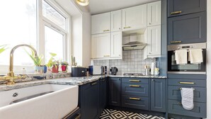 A modern kitchen with a sink, stove, and cabinets. - Walpole Bay Sea Views (Margate)