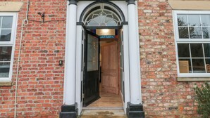 A brick building with a white entrance featuring a decorative archway and a wooden door. - The Old Post Office (York)