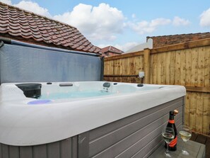 Un bain à remous entouré d’une clôture en bois et une bouteille de vin.