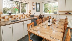 Una cucina moderna con zona pranzo, caratterizzata da un grande tavolo in legno apparecchiato e un forno integrato, oltre a una finestra con vista sul verde.