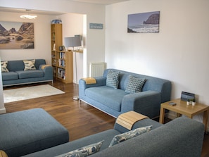 A living room with a blue sofa set, a wooden coffee table, and a bookshelf. - Maceley (Kingsbridge)