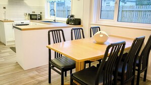 Una cocina moderna con una isla de madera, sillas negras y una mesa de comedor.