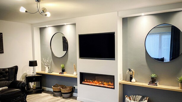 Una sala de estar moderna con chimenea, un televisor de pantalla plana y un espejo redondo.