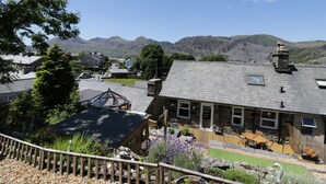 A stone building with a sloped roof, a wooden deck, and a garden with lavender. - Old Post Office (Blaenau Ffestiniog)