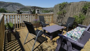 A deck with outdoor furniture, a view of the countryside, and a stone wall. - Old Post Office (Blaenau Ffestiniog)