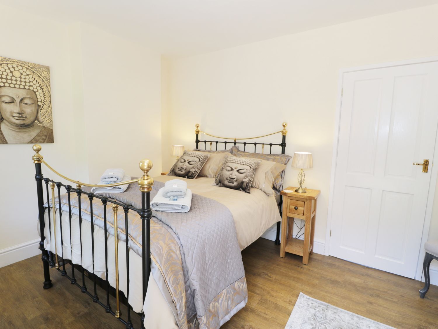 A bedroom with a bed, a nightstand, a door, and a wall-mounted artwork.