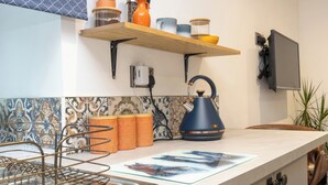 A kitchen with a countertop, a kettle, a shelf with jars, and a tiled backsplash. - Duck Tavern Annexe (Rhosgoch)