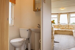 A bathroom with a toilet, sink, and a window with curtains. - Duck Tavern Static (Rhosgoch)