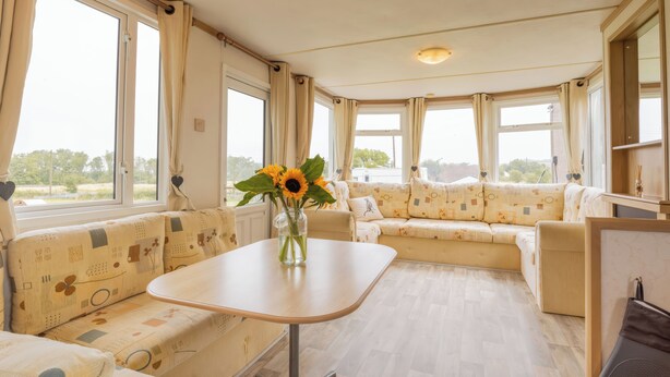 Un salon confortable avec un canapé, une petite table et un vase rempli de tournesols.