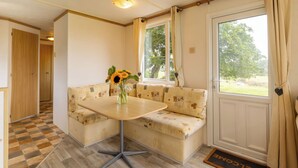 Une pièce chaleureuse avec un canapé, une petite table sur laquelle est posé un vase rempli de tournesols, une porte en bois et une fenêtre avec des rideaux.