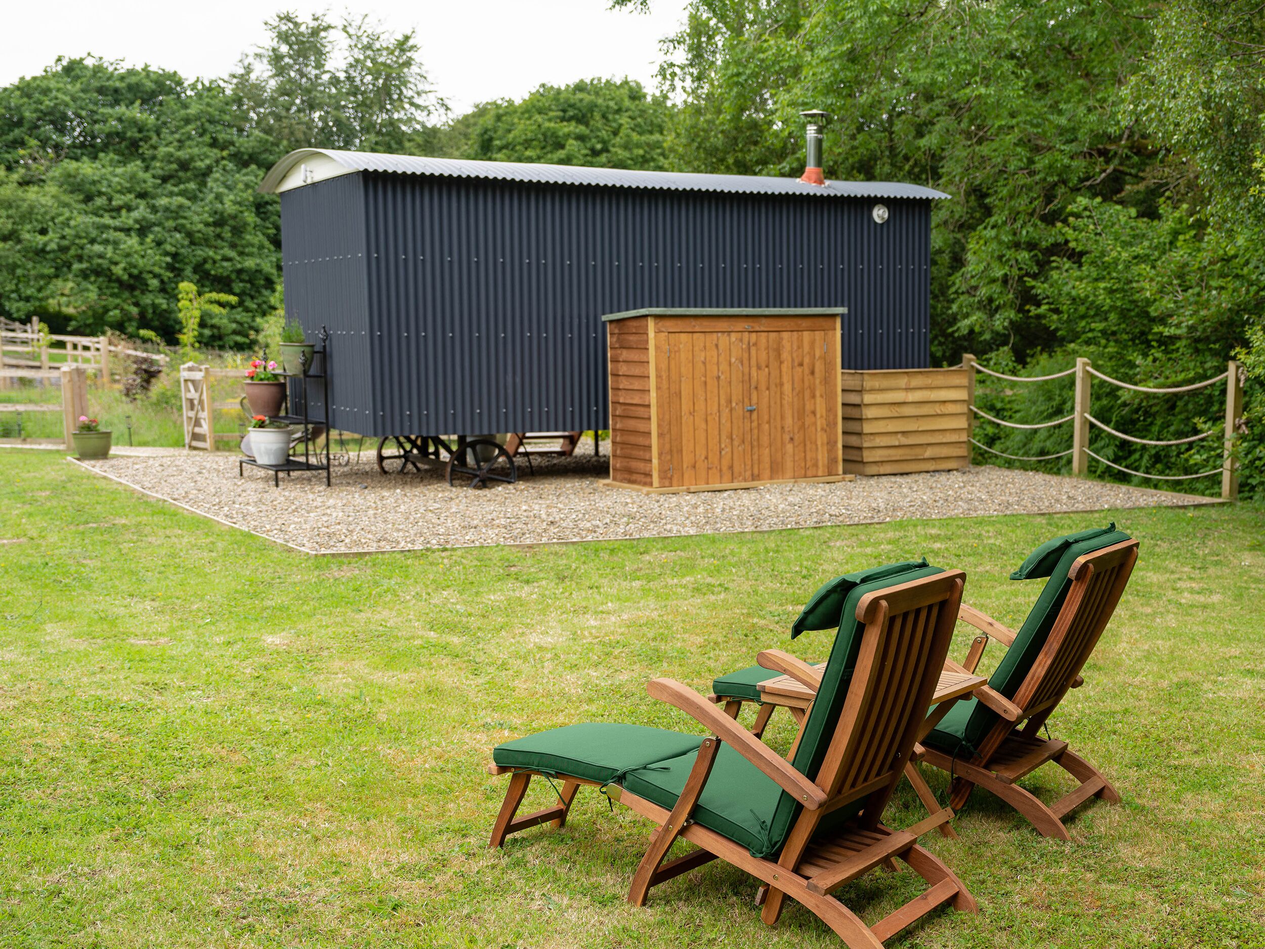 Eine Holzterrasse mit Gartenmöbeln und einem Schuppen in einem Garten.