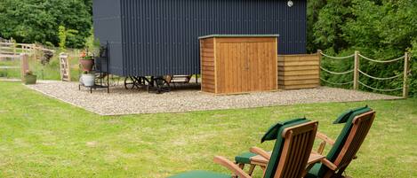 Eine Holzterrasse mit Gartenmöbeln und einem Schuppen in einem Garten.