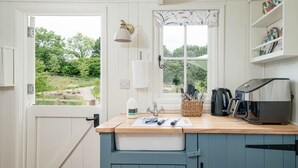 Una cucina con un piano di lavoro in legno, una macchina per il caffè e una finestra vista verde.