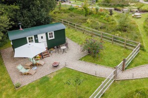 A green house with a patio area, outdoor seating, and a fenced garden. - Collen (Llanarth)