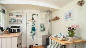 A cozy kitchen with wooden cabinets, a coffee machine, and a hanging apron. - Collen (Llanarth)
