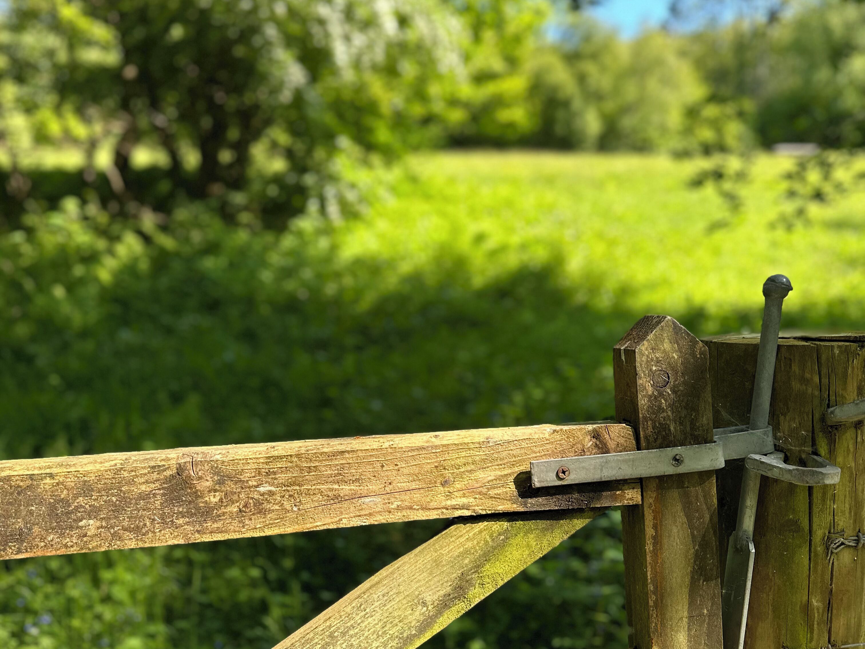 A rustic wooden fence with a metal gate mechanism.